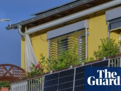 插入式阳台太阳能电池板将首次在英国上市 A man holds a solar panel on a balcony as another man looks on
