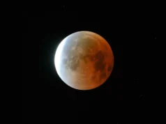 8 月 27 日至 28 日月偏食的各个阶段会发生什么 A full moon is shown in a black sky during a lunar eclipse, with its right side glowing red in Earth's shadow.