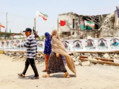 伊朗称在美国结束海上封锁之前不会重新开放霍尔木兹海峡 People walk past the destroyed Shajareh Tayyebeh primary school in Minab in Iran’s Hormozgan province, on Monday