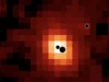 科学家在遥远星系内发现3个濒临碰撞的超大质量黑洞 A pixelated reddish image. There are three black circles showing where the three black holes are located.