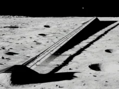 埃隆·马斯克表示 SpaceX 到 2028 年将实现 5000 亿美元的收入 Illustration of a long railway-like structure on the moon, with a tiny-looking earth in the background