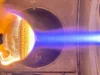火灾中的隔热罩| 2026 年 8 月 26 日当天的太空照片 On the left is a heat shield that is bright orange and yellow engulfed in flames while on the right are bright blue and white flames pointed at the object.
