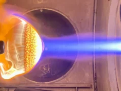 火灾中的隔热罩| 2026 年 8 月 26 日当天的太空照片 On the left is a heat shield that is bright orange and yellow engulfed in flames while on the right are bright blue and white flames pointed at the object.