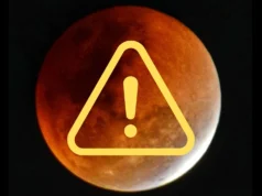 今晚,令人印象深刻的月偏食将使数百万人的月亮变成诡异的红色 graphic showing a blood red moon during a lunar eclipse with a small portion of the moon still illuminated bright white. there is a yellow exclamation mark within a triangle graphic in the foreground.