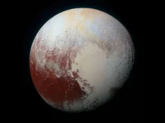 冥王星失去行星地位已有20年了。它会重新获得冠军头衔吗? A view of white sections of a world with some reddish areas toward the left.