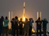 再见,猎鹰 9 号:SpaceX 计划在 Starship 启动并运行后退役主力发射器 a row of people in the distance take photos of a rocket far away but large in frame.