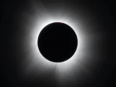在太空的这一天! 1914 年 8 月 21 日:日全食探险队因第一次世界大战坠毁 A black circle against a black background surrounded by white wispy tendrils