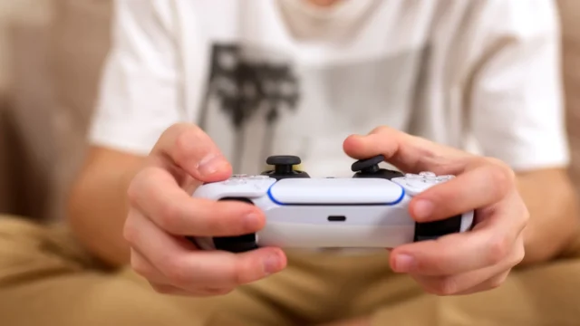 How to fix stick drift on PS5 and Xbox controllers: A person playing a game with a PS5 DualSense controller