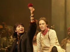 “Headstown”开始流媒体播放 – 在这里可以观看“Headstown”火腿 An image collage containing 1 images, Image 1 shows A woman in a dark coat and bandana holds up a red flower while singing, next to a man in a white shirt and red bandana